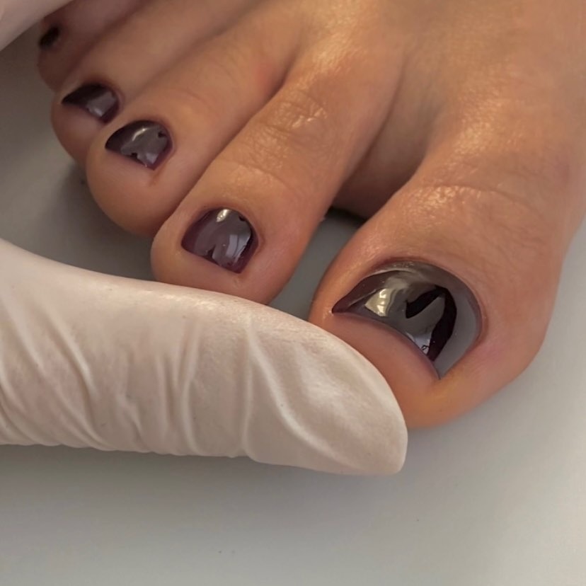 Un primo piano di una pedicure color bordeaux