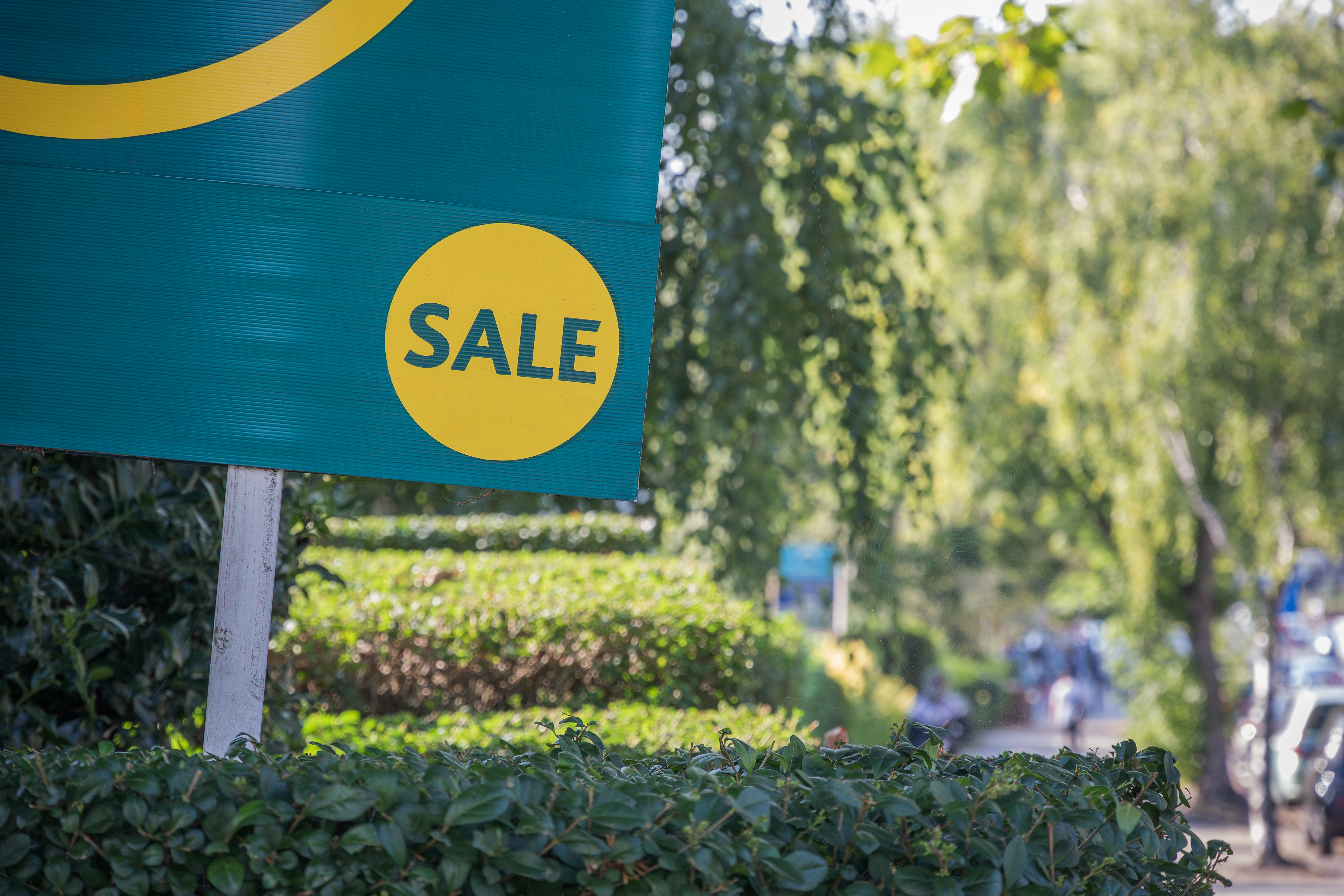 House for sale sign reads "sale" in a garden outside of a property.