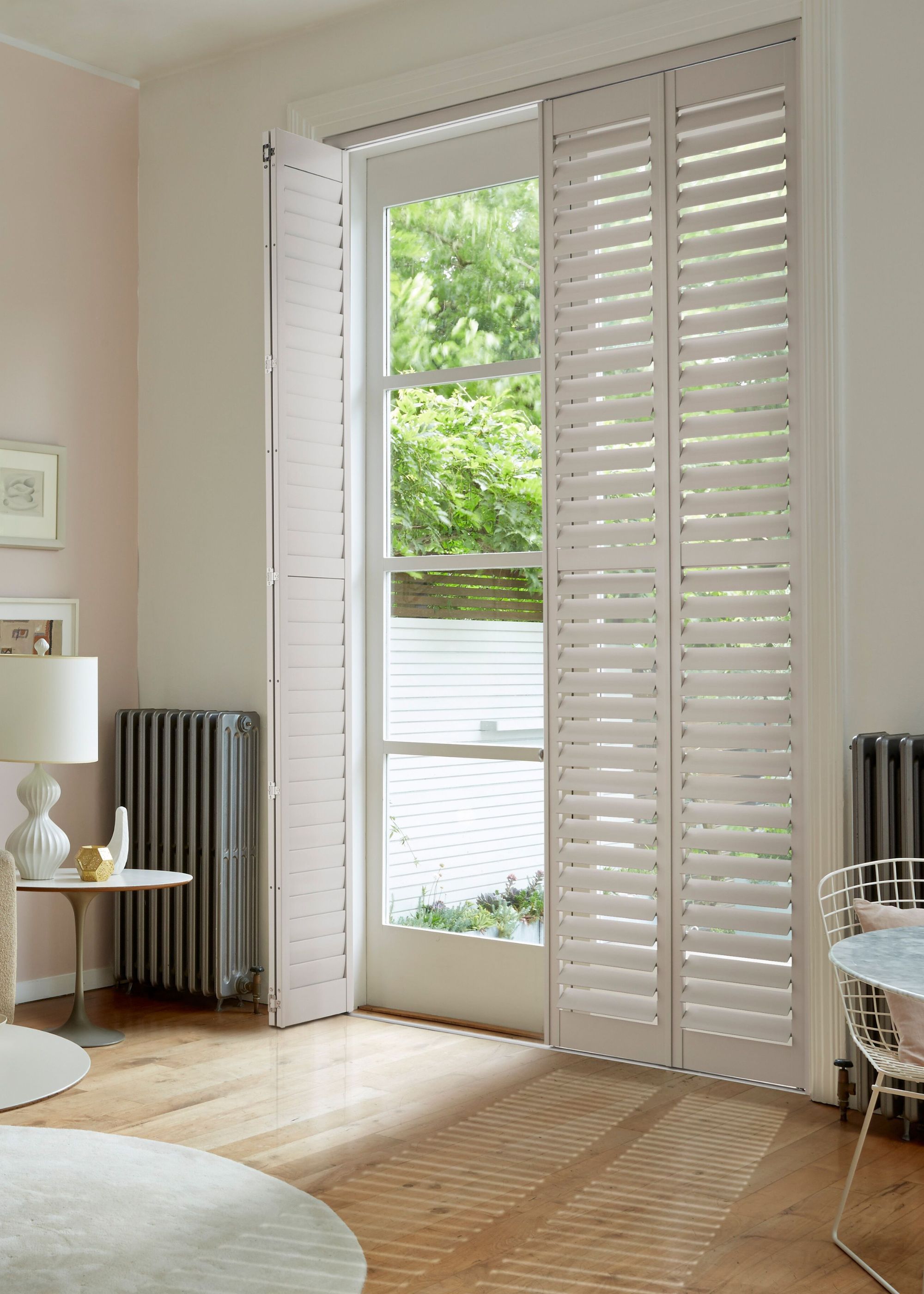A modern living room with French doors with white full-length shutters.