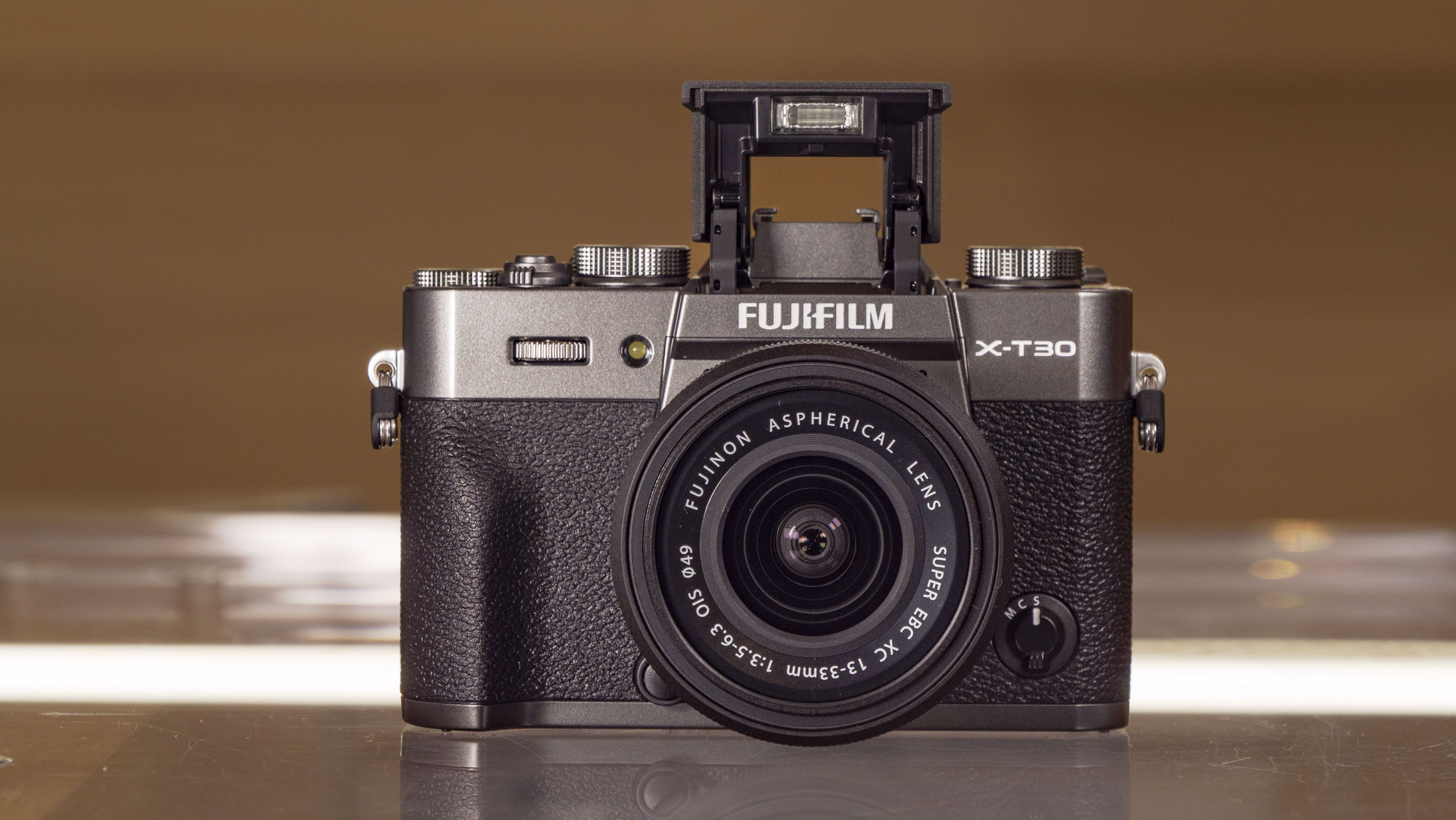 Fujifilm X-T30 III camera with pop-up flash out, on a glass table