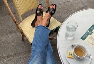 best slide sandals, a close up photo of a woman wearing black hermes slide sandals and jeans