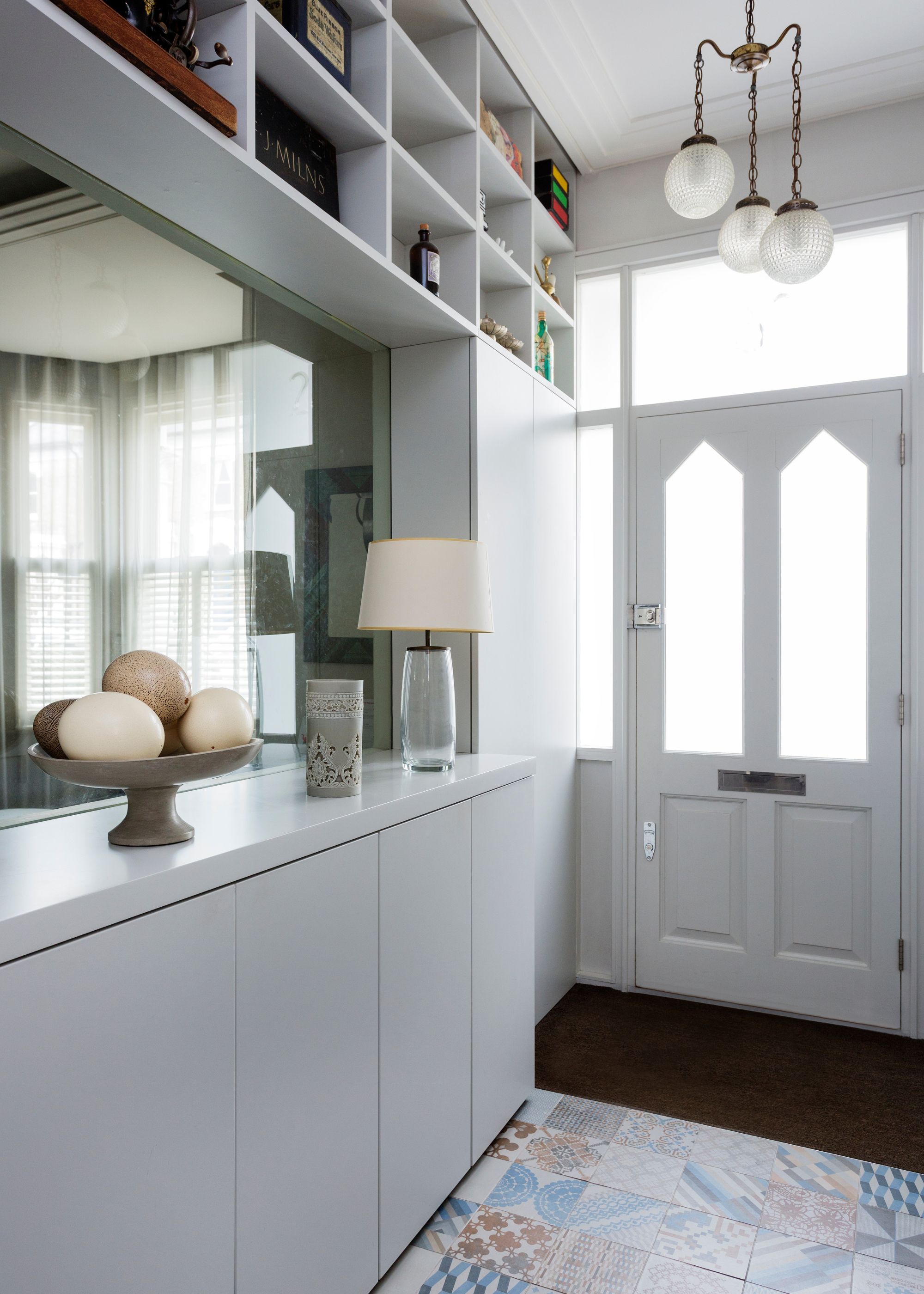 modern entryway with white built-in shelving and mirrored wall