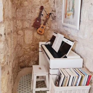 room with white piano books shelve and guitar