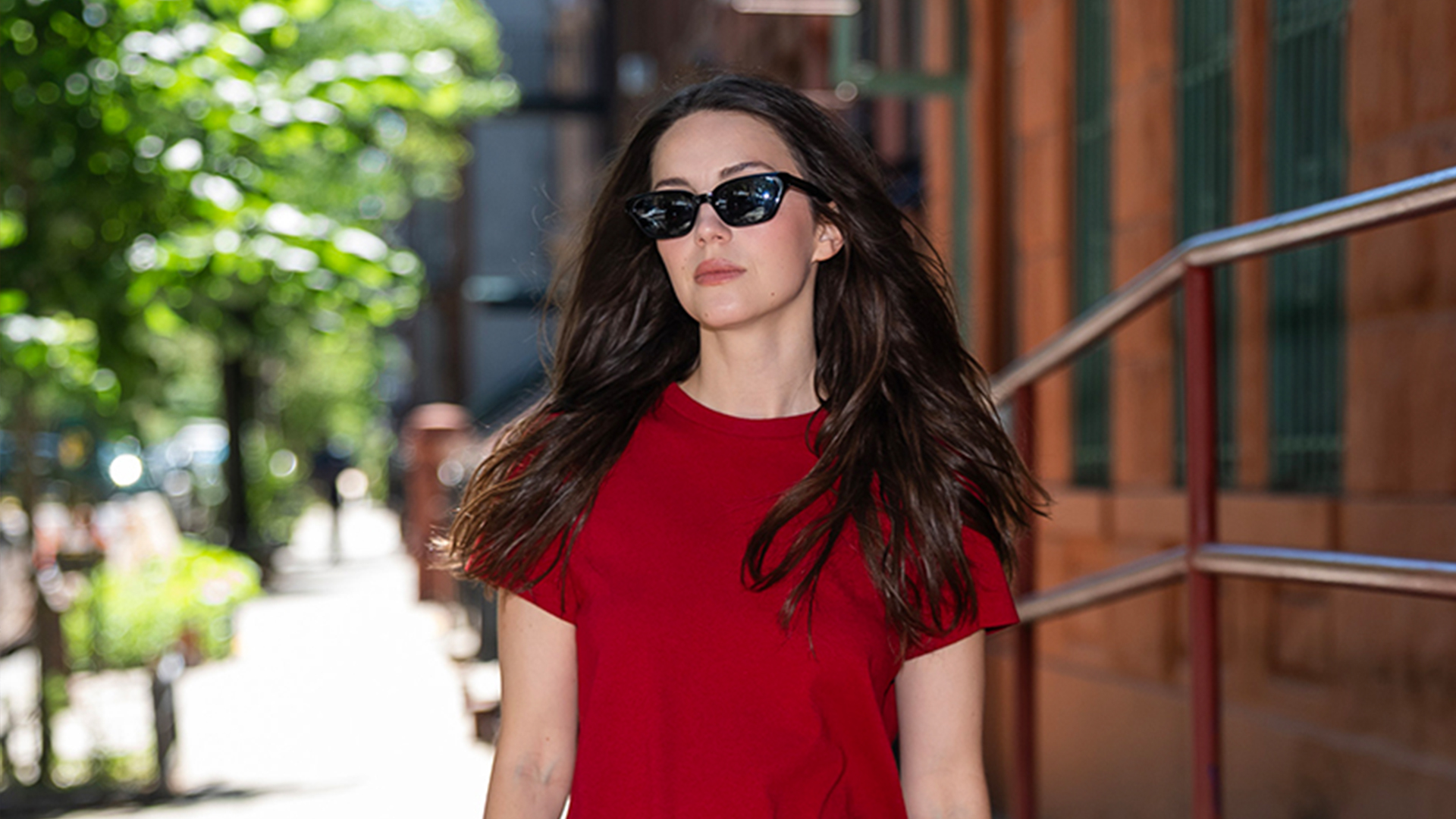 Ella Hunt wearing a red t-shirt, baggy shorts, and red pumps.
