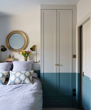 Pastel blue bedroom with light blue bedding, gold round mirror above bed and gold lamps