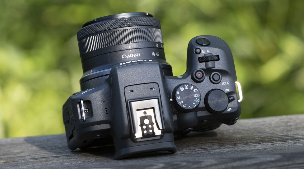 The Canon EOS R10 camers sitting on a wooden bannister