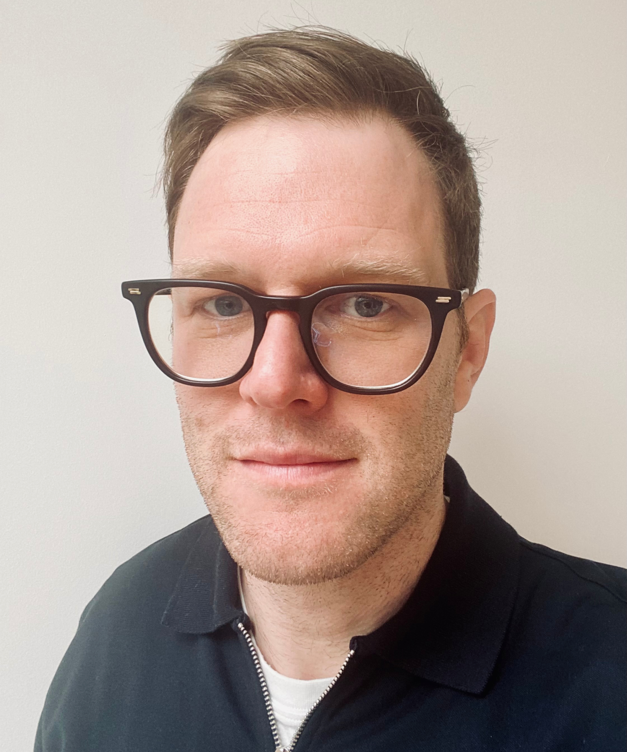 headshot of male with short hair, glasses and blue shirt