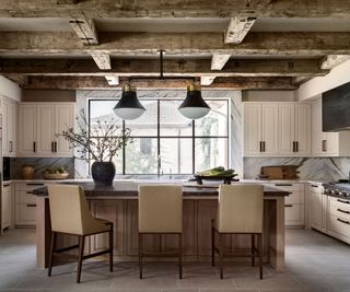 kitchen with big island and wooden beams with cream bar stools