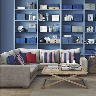 living room with open shelf blue walls and grey sofa