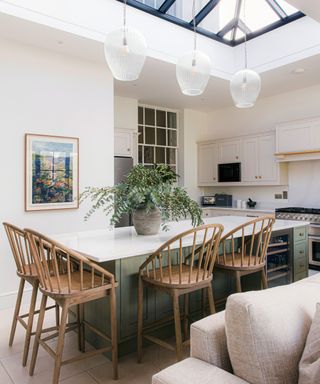 open plan kitchen with roof lantern and large green kitchen island with wooden bar stools