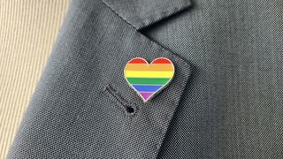 An LGBTQ+ heart-shaped pin on a jacket lapel