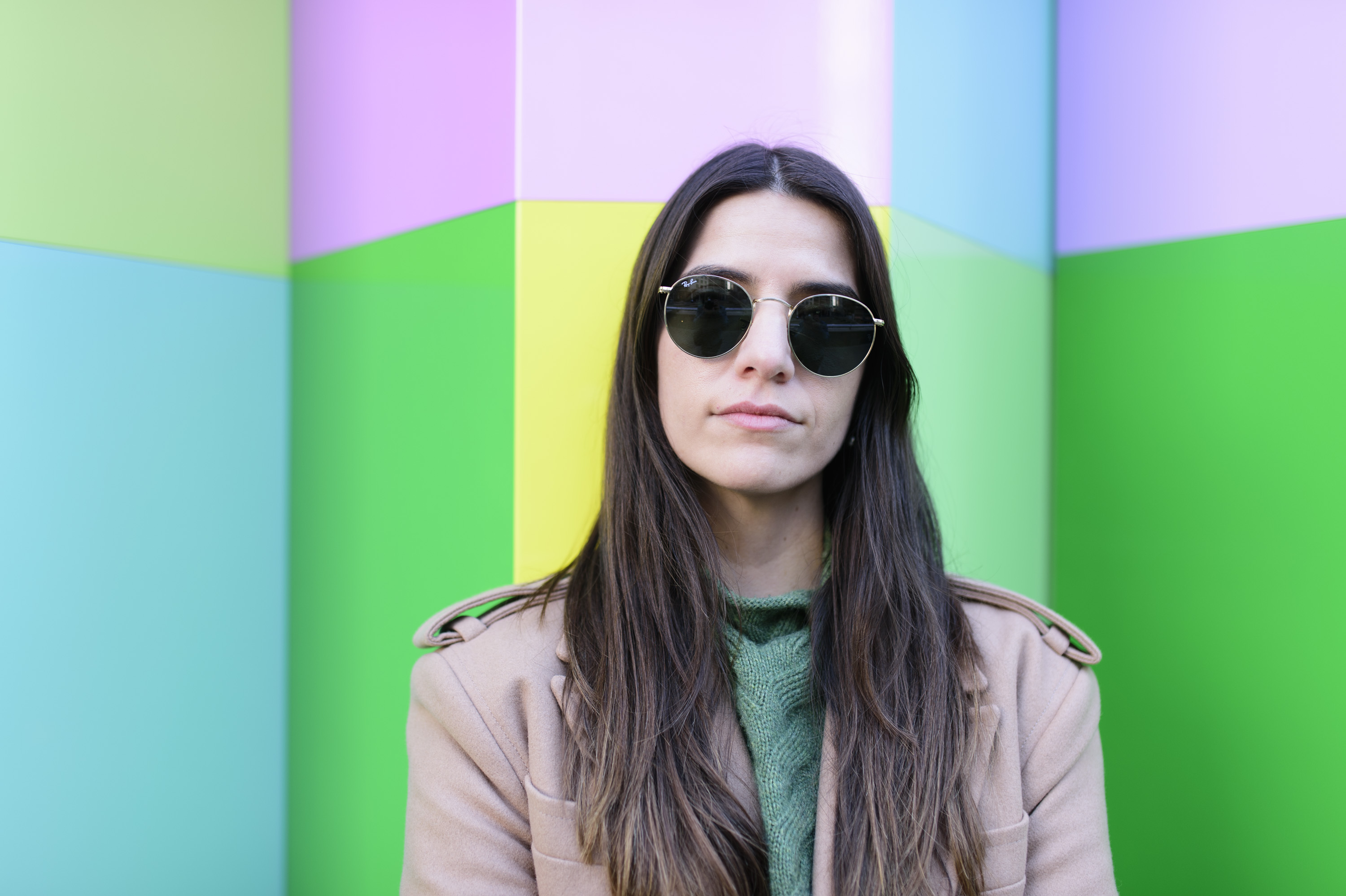 Portrait of sunglass-wearing lady with bright multi-colour wall backdrop