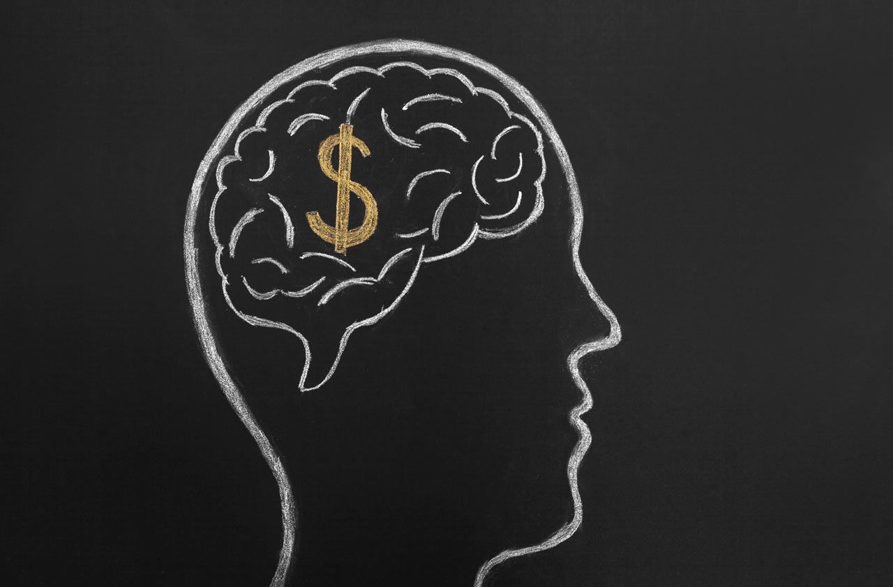 A chalkboard drawing of a man&amp;#039;s brain with a dollar sign in it.