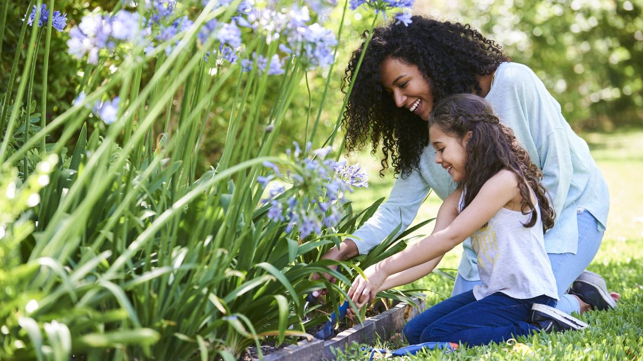 A mother and daughter smile and garden