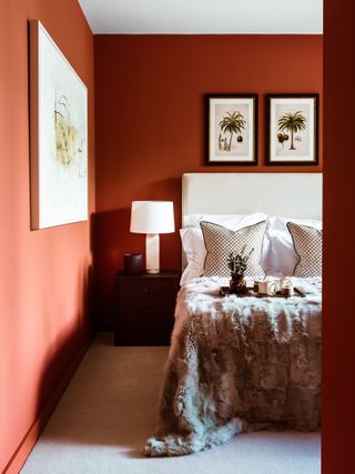 An earthy red bedroom with paintings on the walls