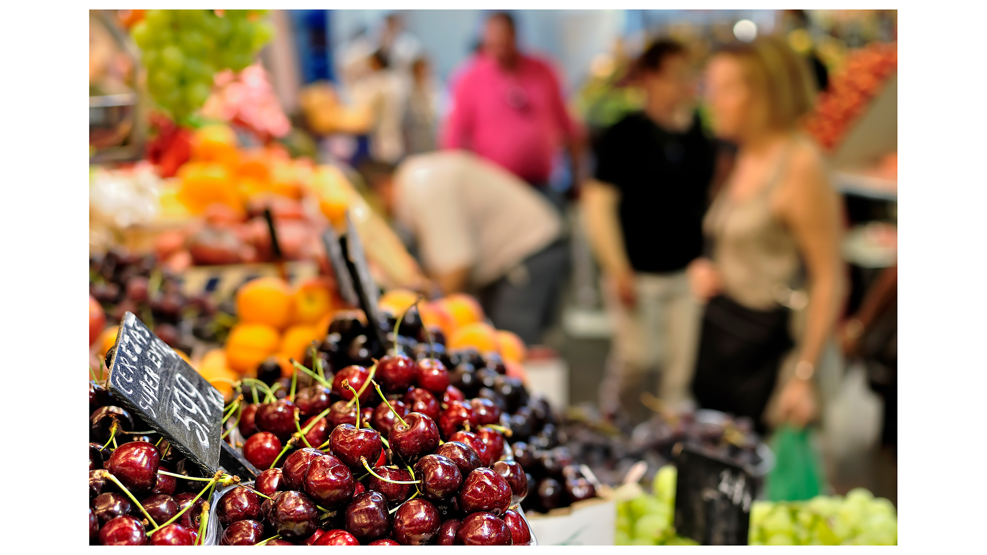 Fruit produce in foreground with customers in blurred background at Barcelona’s historic La Boqueria market