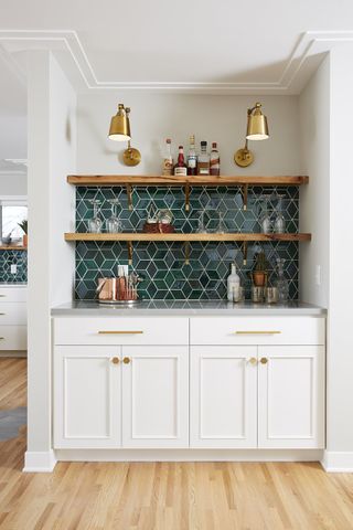 Green mosaic-style kitchen tile ideas in a white kitchen alcove with wooden shelf and gray counter top.
