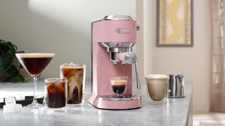 The De'Longhi Dedica Duo in Rose on a countertop with drinks