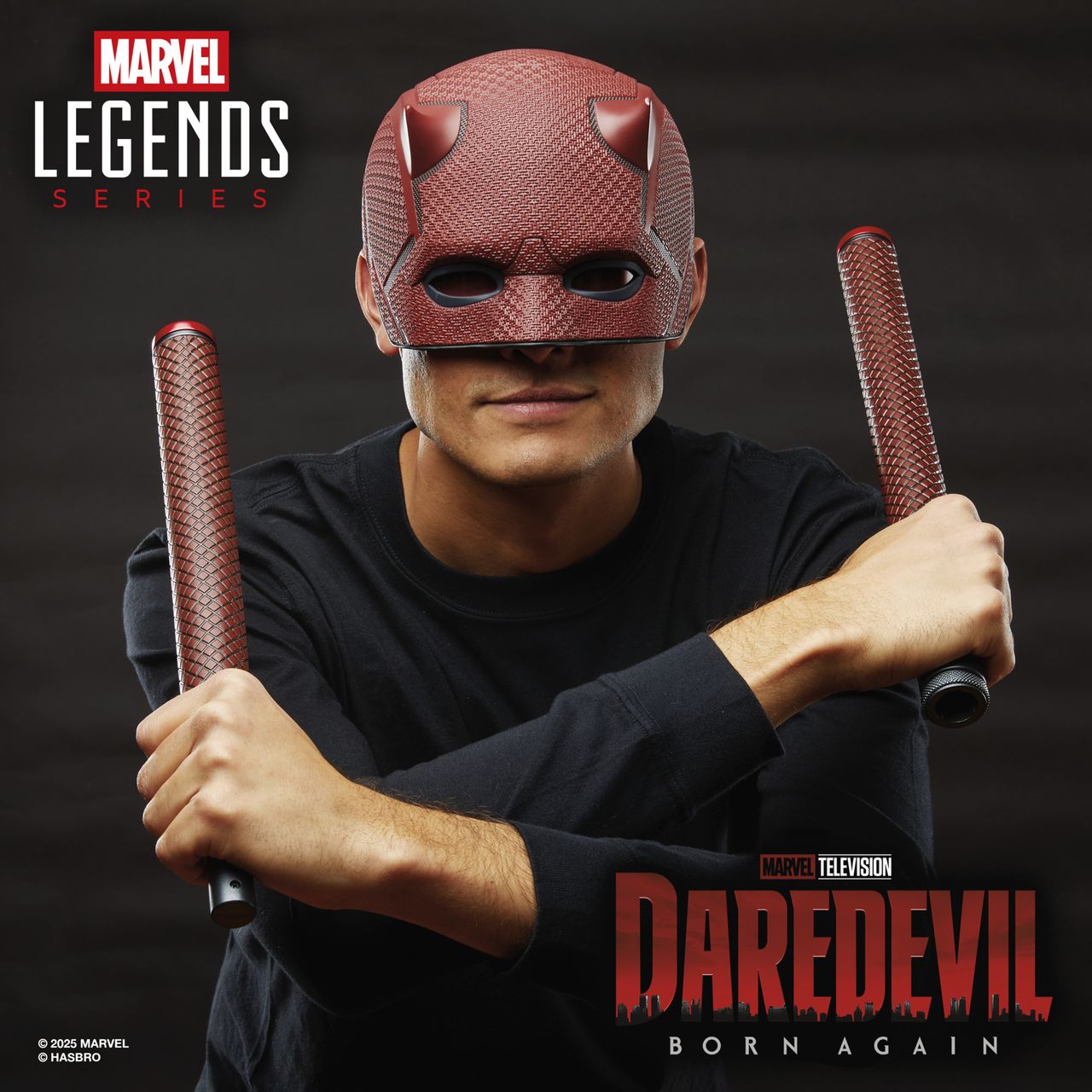 A man smiles while wearing a Marvel Legends Series Daredevil replica helmet with Billy Club against a dark background with a city-scape pattern, alongside the Marvel Legends Series and Daredevil: Born Again logos