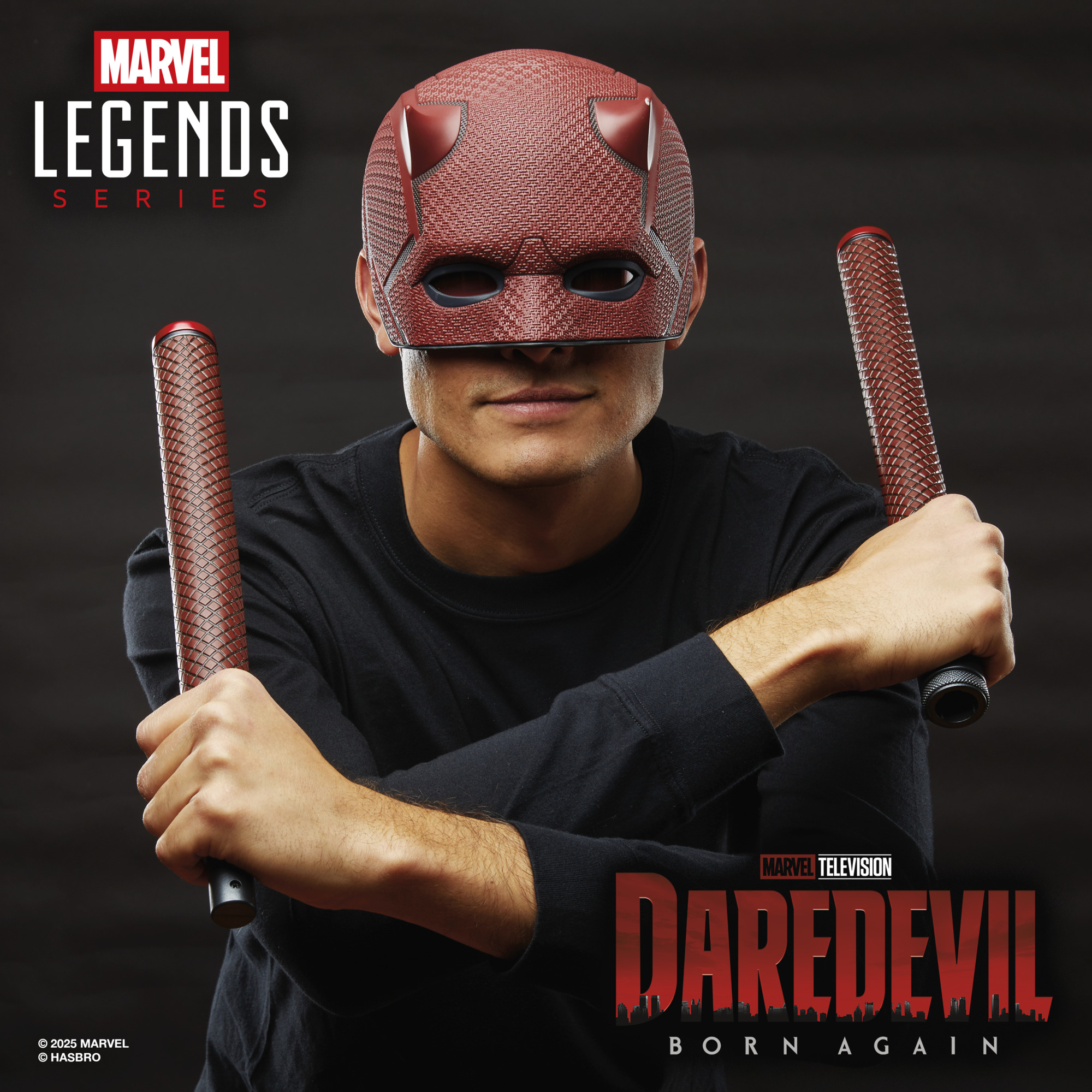 A man smiles while wearing a Marvel Legends Series Daredevil replica helmet with Billy Club against a dark background with a city-scape pattern, alongside the Marvel Legends Series and Daredevil: Born Again logos