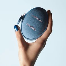a picture of a model's hand holding a denim hand cream case 