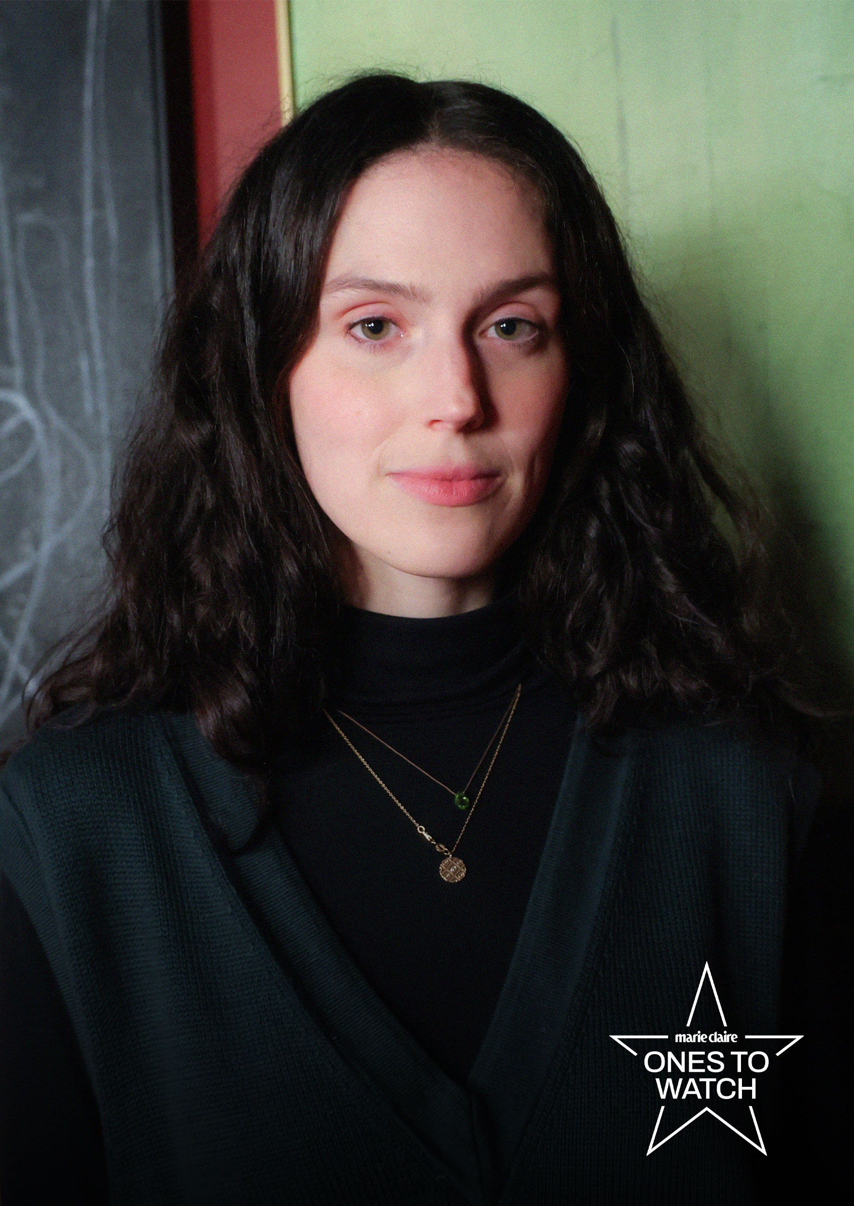 director eva victor wears a black top and poses against a green backdrop