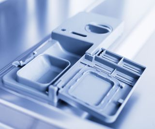 Up close of an clean, empty dishwasher detergent dispenser