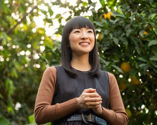 Marie Kondo on Sparking Joy, holding her hands together in front of a tree