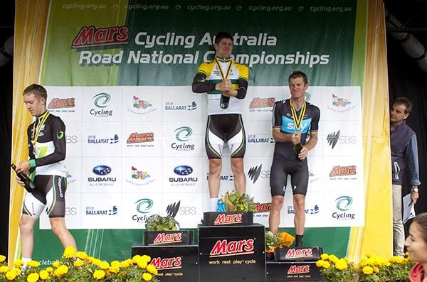 SBS presenter Michael Tomalaris takes cover from the podium spray in the men's elite time trial championship.