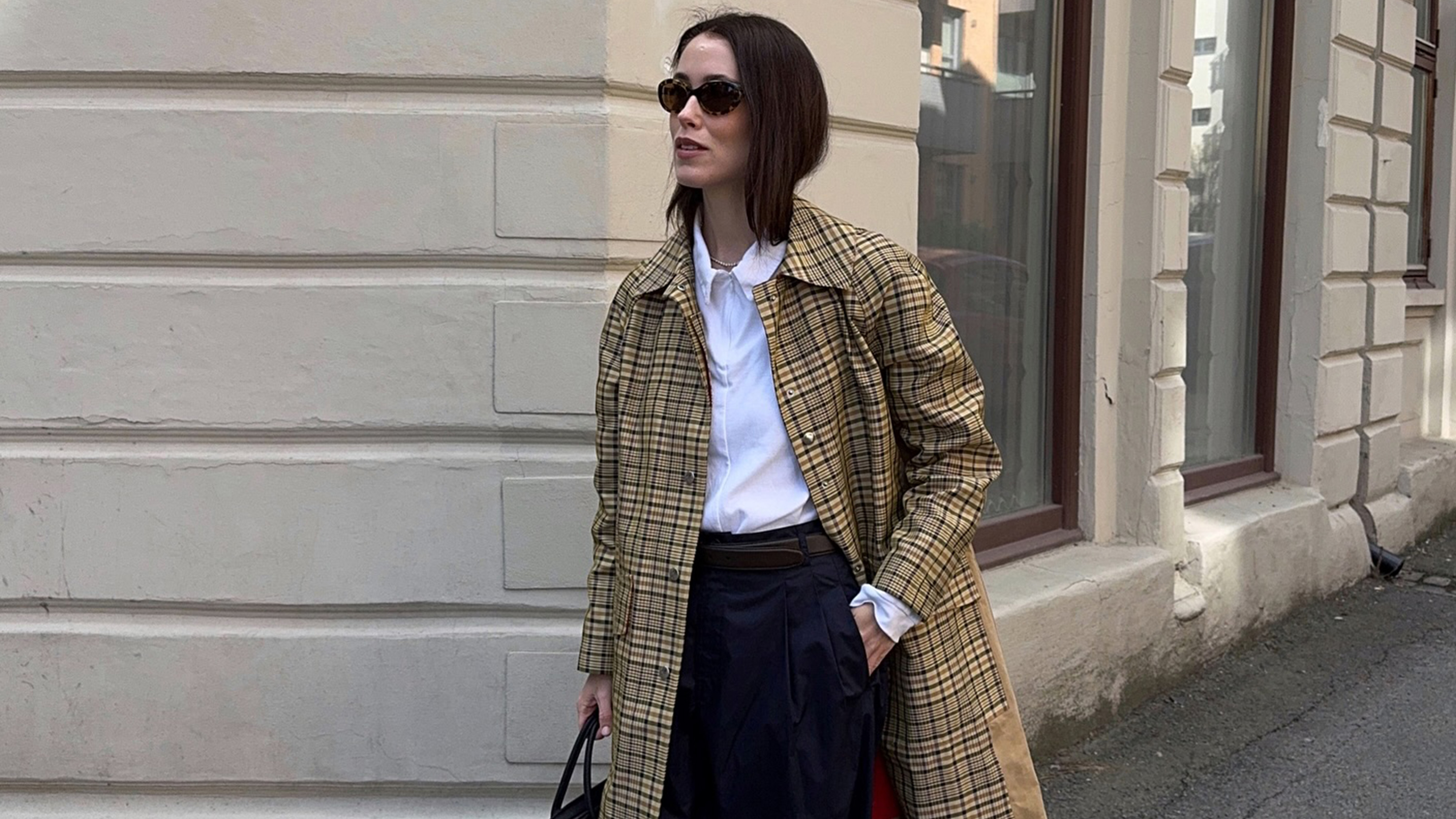 Annabel wears a plaid jacket, white top, black pants, and brown sneakers.