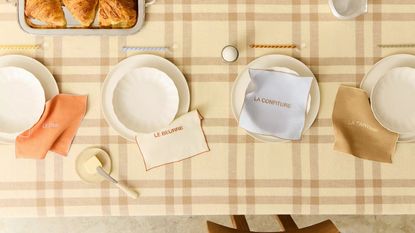french bistro inspired tablescape by zara home with a butter yellow checked tablecloth, french pastel napkins, twisted glass spoons, and croissants