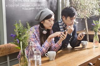 Asian couple looking at their mobile phones on first date