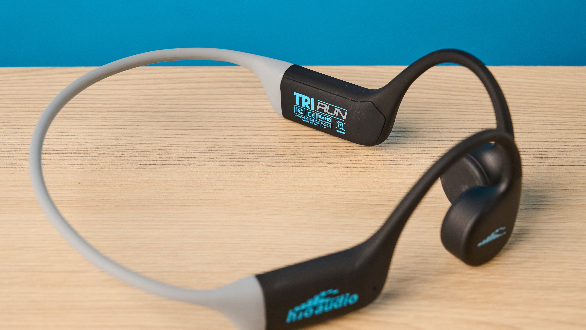 the h2o audio tri run bone conduction headphones photographed against a tom's guide blue background