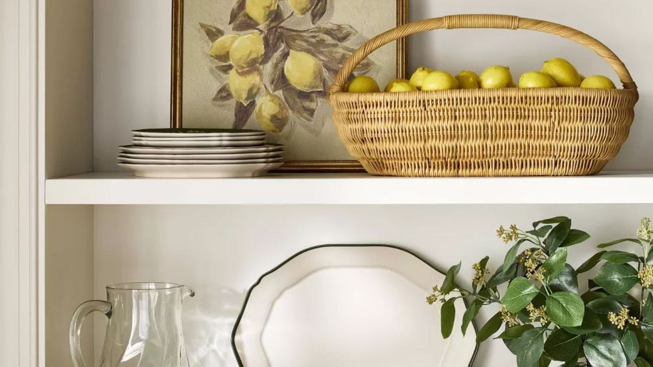 kitchen shelves with a woven basket filled with lemons and a vintage-style lemon painting with stacked crockery