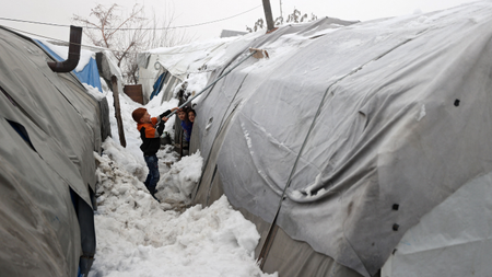 A child brushing snow off a tent