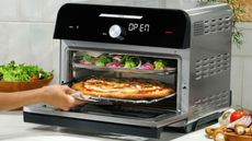 Instant Omni Plus Oven on a countertop with a pizza and vegetables