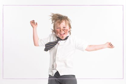 School kid jumping up with school uniform on and muddy face