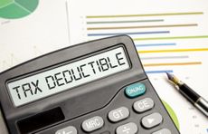 "tax deductible" on calculator screen with fountain pen and paper printed with colorful lines