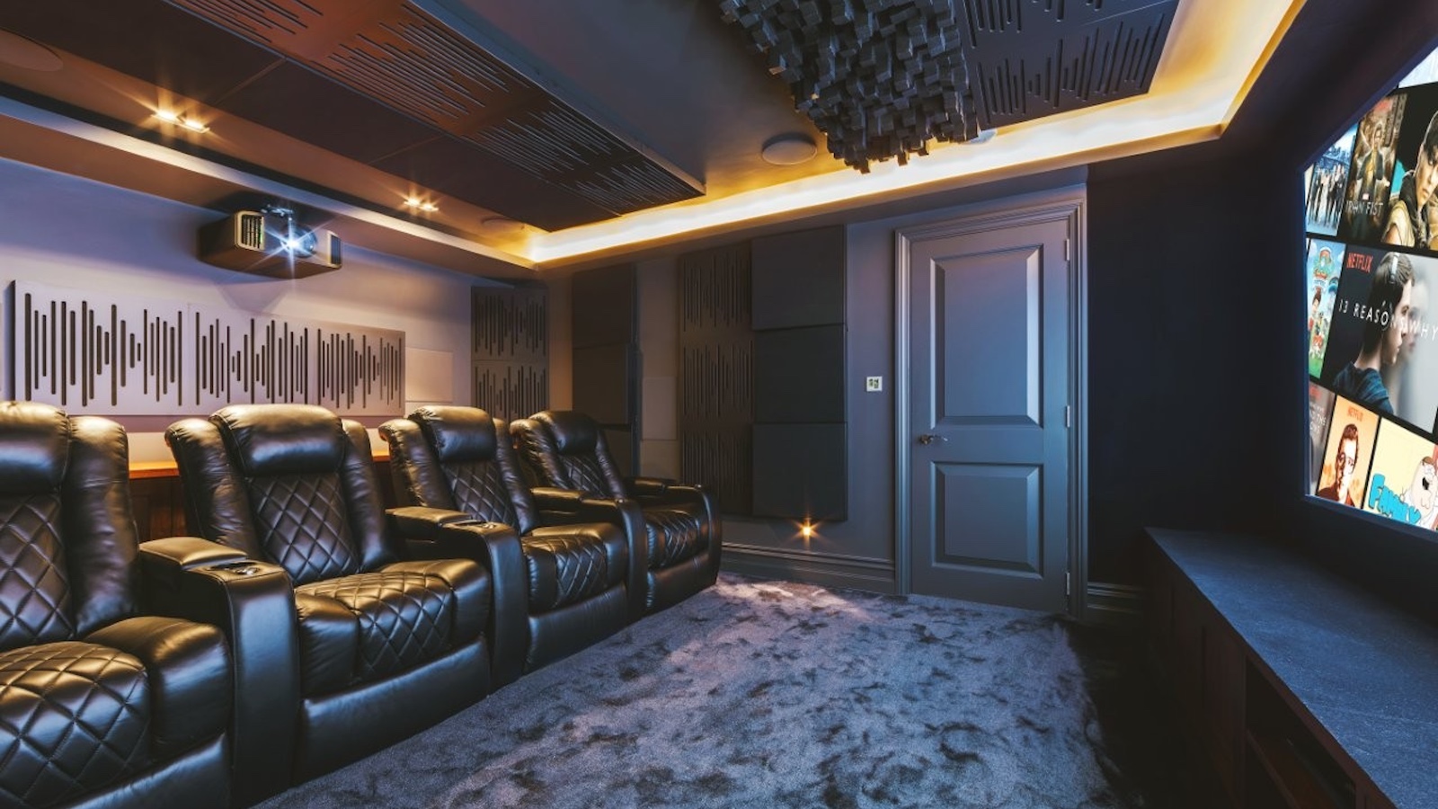 A photo of a custom-installed home cinema room featuring a 4K projector, theatre seating and clever acoustic treatment