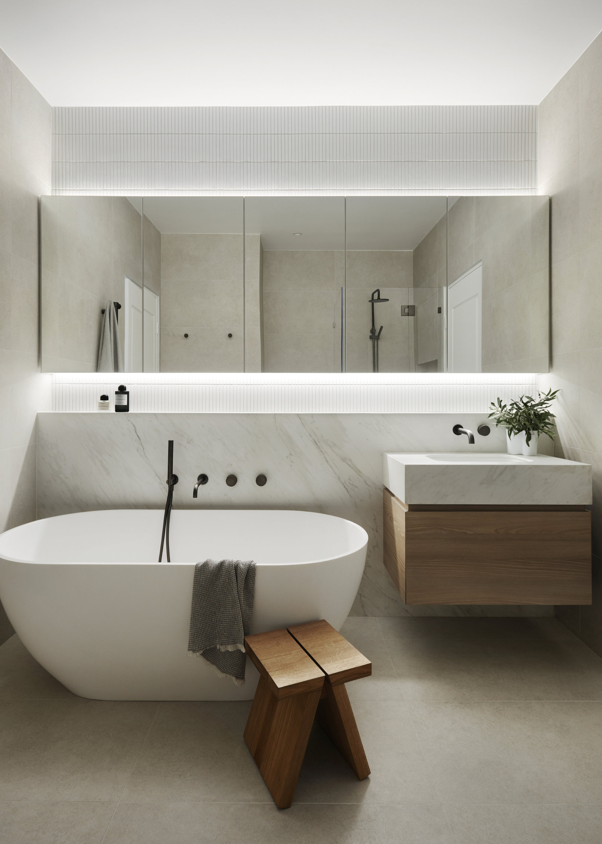 A bathroom with LED lights behind the mirror and a large bath tub in the bathroom as well as a sink with a plant on top of it