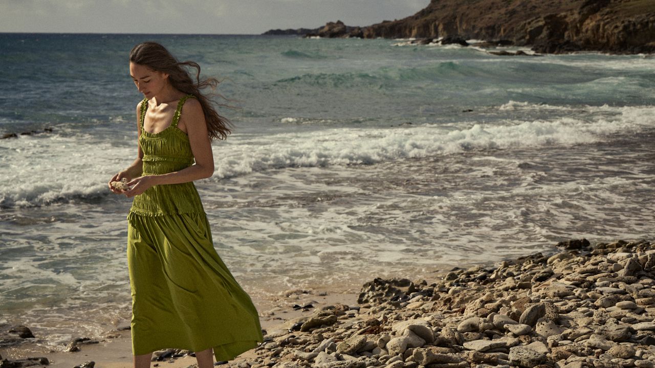 Model wearing green smocked Dôen dress on the beach.