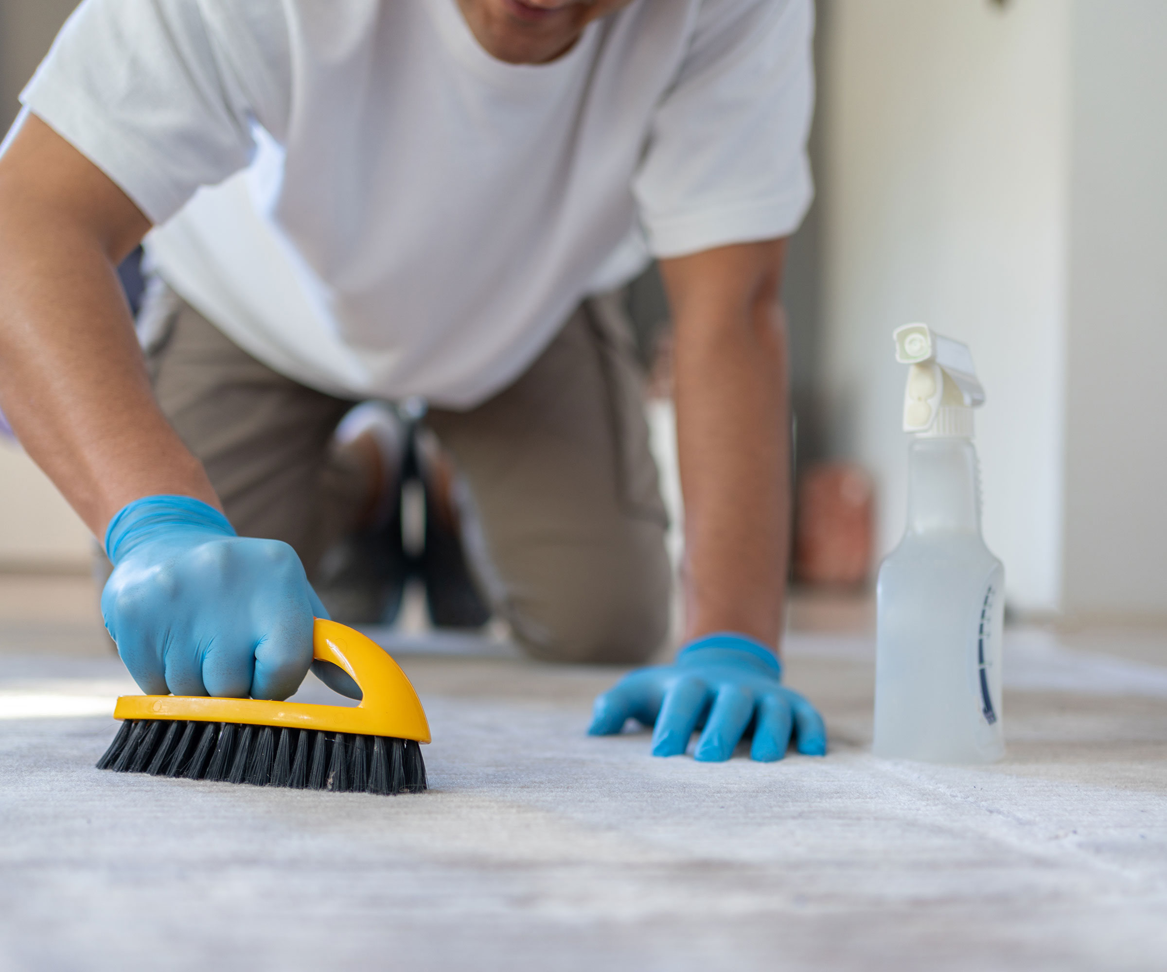 man using yellow scrubbing brush to clean carpet