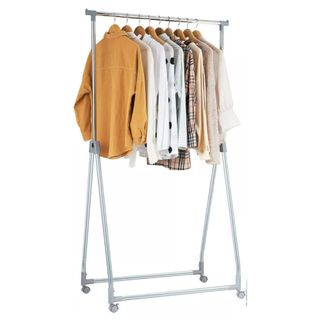 A metal clothes rack with yellow, white, and brown shirts hanging from it