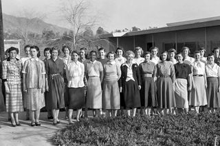 24 women pose outside with mountains in the background