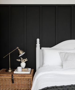 Guest bedroom with black wall paneling and bed with white bedding