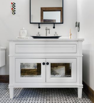 white vanity unit in white powder room with black sink and mirror