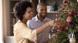 A man and woman decorating a Christmas tree