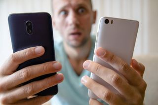 Ein Mann hält zwei Smartphones in den Händen, als könne er sich nicht zwischen beiden Modellen entscheiden
