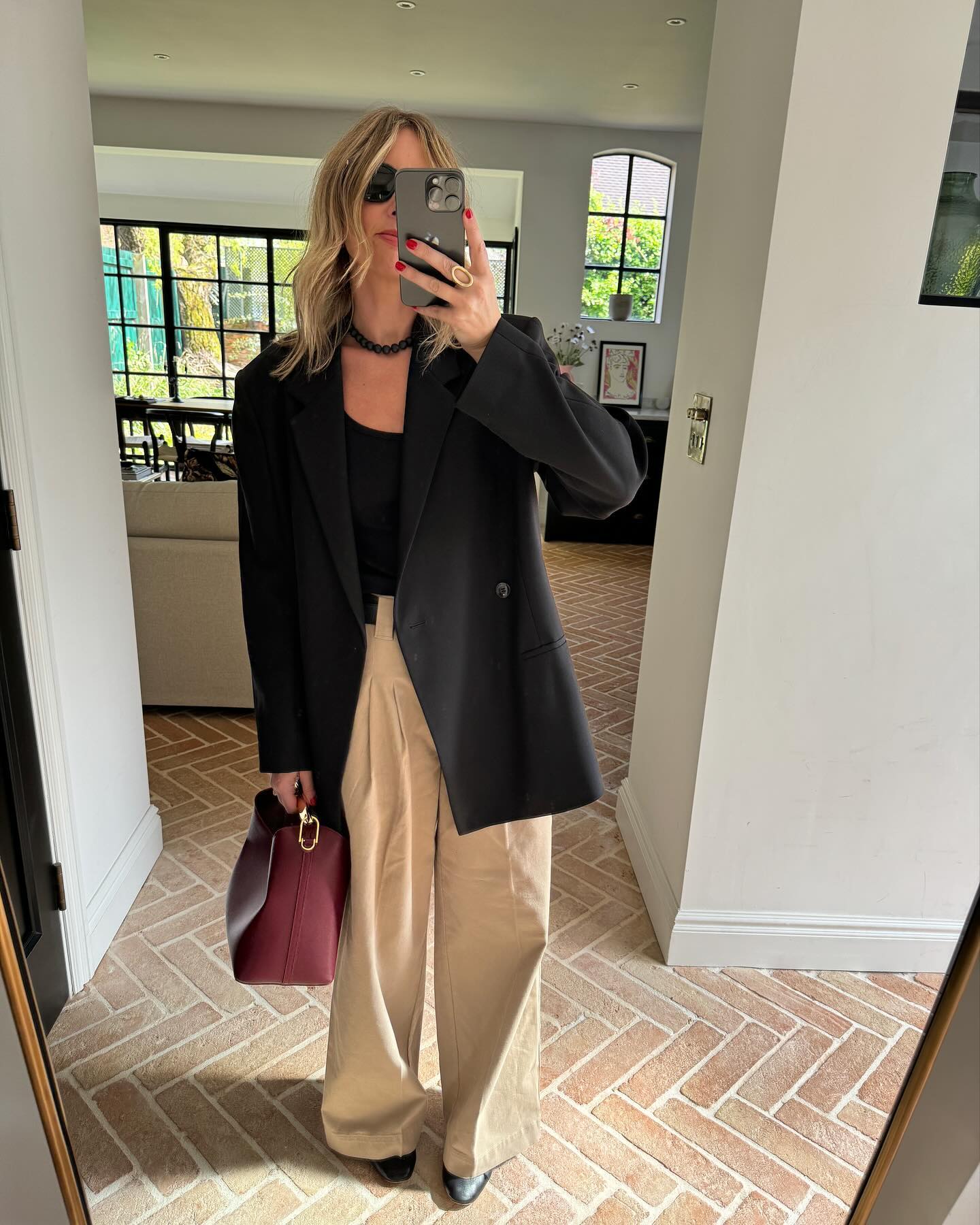 Woman wears black blazer, beige trousers, red handbag