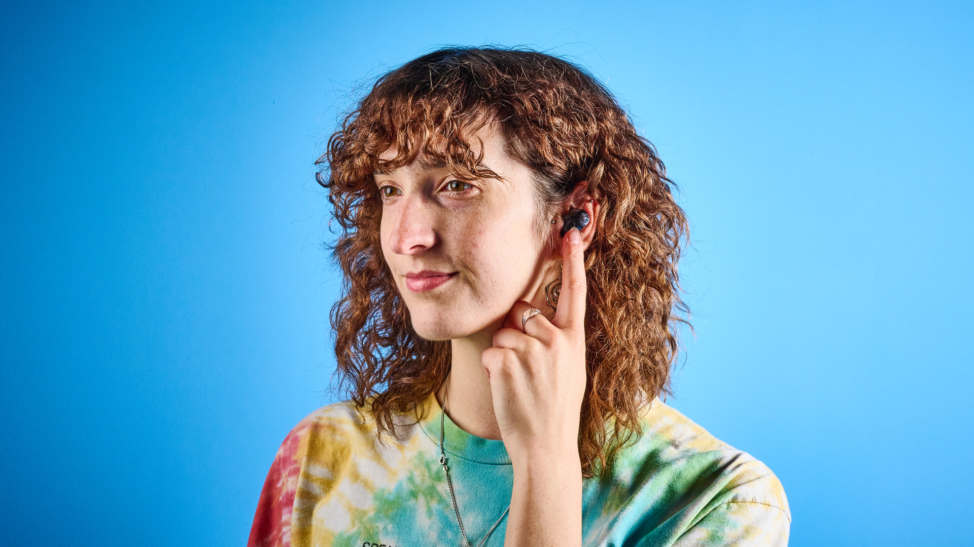 the sennheiser momentum 5 true wireless earbuds in navy photographed with the blue tom's guide background
